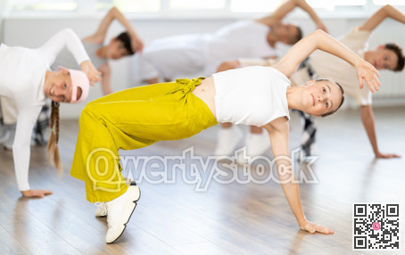 Group of young friends learn group dances - low break and breakdance in studio