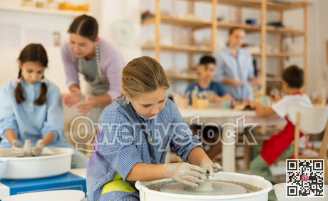 Girl working at a potter's wheel with clay