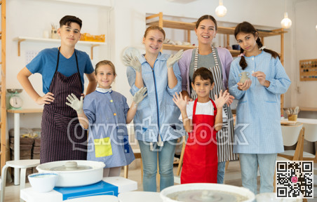 Happy children posing female teacher in pottery workshop