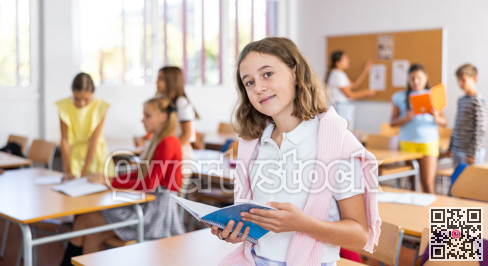 Portrait of smiling schoolgirl with copybook in classroom