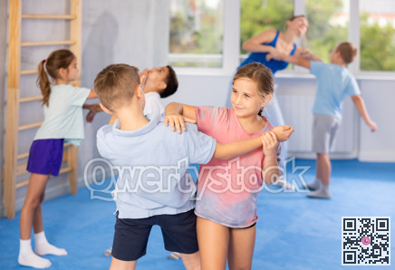 Boys and girls in gym perform basic elements of krav maga self-defense system.