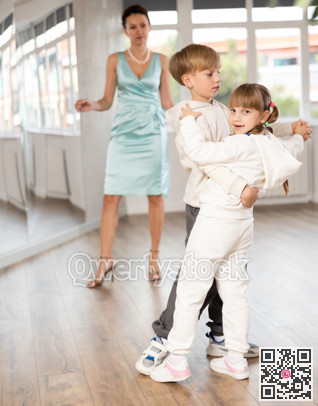 Preteen boy and girl refining slow foxtrot technique in dance hall
