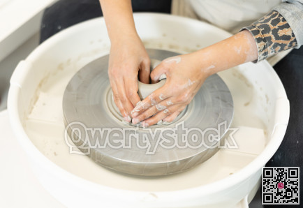 Close-up of woman's hands shaping clay on pottery wheel