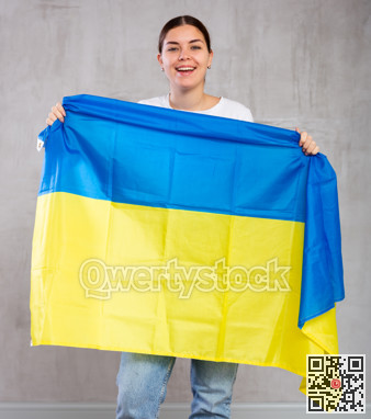 Joyous young woman holding Ukraine flag against unicoloured background