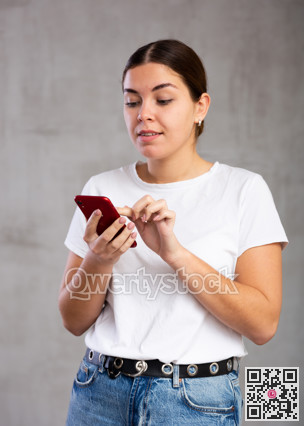 Focused young woman reading message on phone