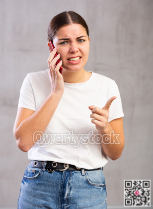 Angry young woman talking on mobile phone