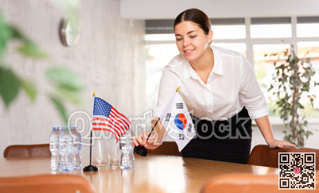Young female attendant putting up flags for international negotiations between usa and south korea