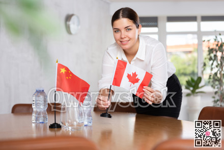 Young female attendant putting up flags for international negotiations between china and canada