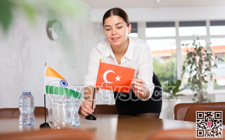 Young female attendant putting up flags for international negotiations between india and turkey