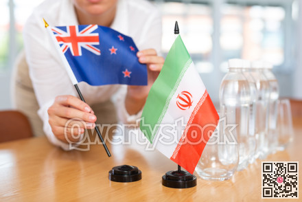Woman secretary prepares an office for negotiations - she places flags of Iran and Australia table