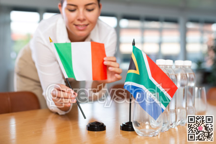 Little flag of South Africa on table and flag of Italy put next to it by young woman