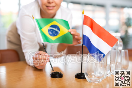 Unrecognizable girl set midget flags of Netherlands and Brazil before international negotiations