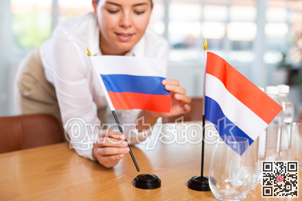 Employee of delegation prepares negotiating table - sets up flag of Russia and Netherlands