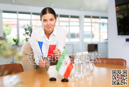 Woman secretary prepares the negotiating table - arranges flags of France and Iran