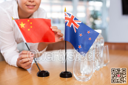 Preparing for business negotiations - woman sets small flags of countries of China and Australia on table