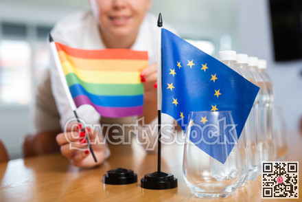 Preparing for business negotiations - woman sets small flags of countries of European Union and LGBT on table