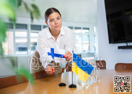 Young lady sets miniatures flags of Ukraine and Finland for international negotiations