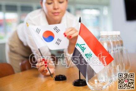 Employee of delegation prepares negotiating table - sets up flag of South Korea and Iraq