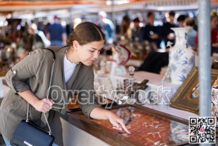 Young woman looking at vintage items at flea market