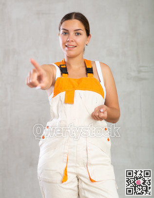 Young woman posing in work overalls in studio