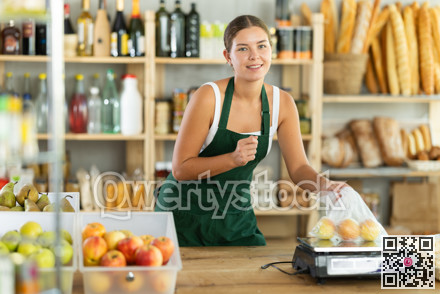 Girl selling food products weighs apples on scales