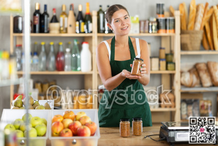 Young female seller offering lentils in grocery store