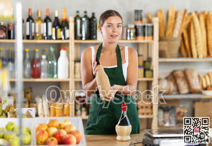 Female salesperson offers to buy bottle of wine in liquor department of grocery supermarket