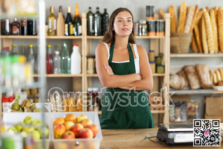 Young woman seller at counter in grocery store