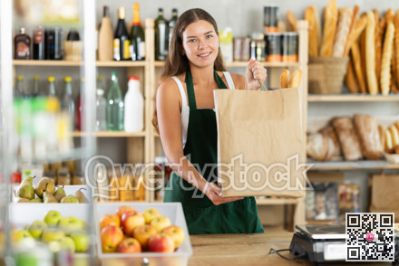 Young woman with bag of baguettes in grocery store
