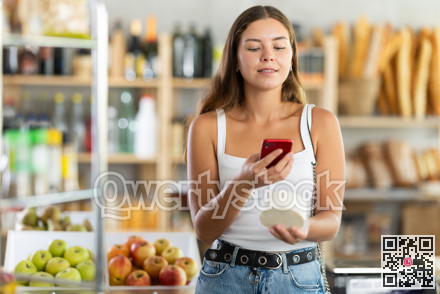 Female shopper scans QR code on cheese label using smartphone. Checking products in supermarket