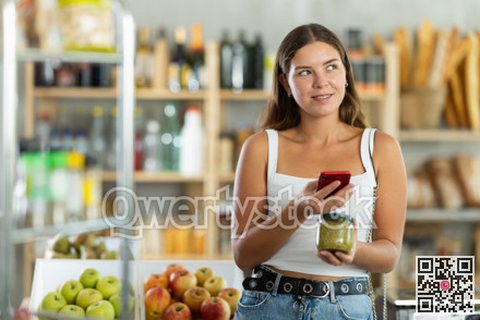 Female shopper scans QR code on green peas jar label using smartphone. Checking products in supermarket