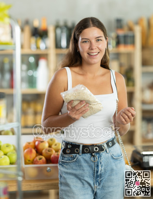 In grocery supermarket, female shopper chooses oat flakes for breakfast