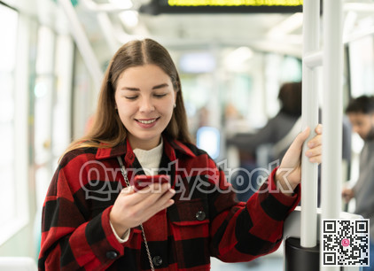Girl is standing with phone in tram car, getting to work