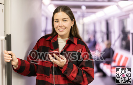 woman stands in the subway and holds on to a handrail