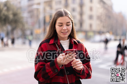 Young woman standing outside and holding phone