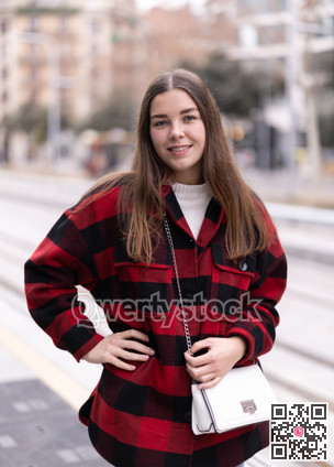 Girl is standing on street platform, waiting for tram to arrive