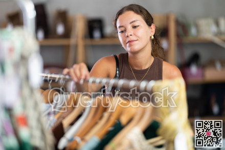 Young woman comes to boutique and looks at clothes