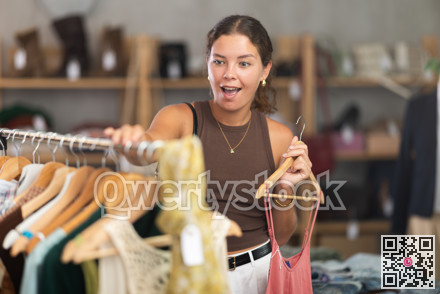 Girl customer choose crop top in store, and buyer carefully examines product.