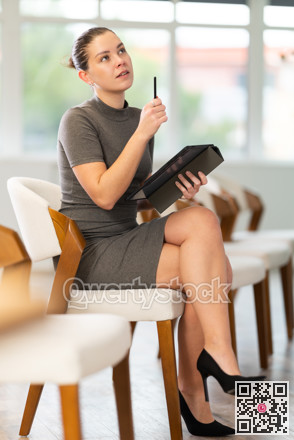 Young girl student dressed in business dress sitting and listening lecture, taking notes on tablet in lecture hall