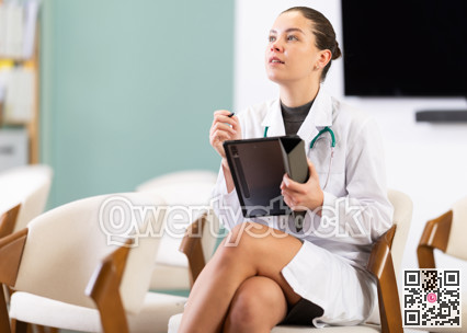 Female medical student listening to lecture in classroom with tablet