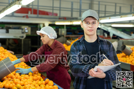 Positive male worker fills out a document at a citrus processing plant.