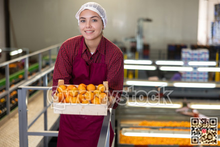 Smiling young female fruit warehouse worker with box of mandarins