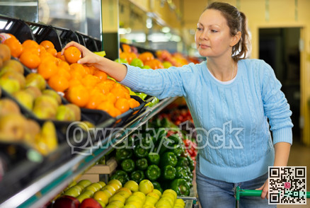 woman buys juicy tangerines in supermarket