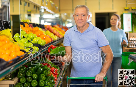 Elderly man purchaser buying pepper in grocery store