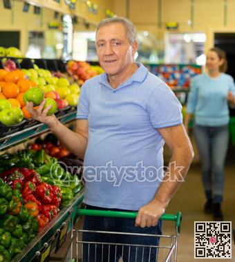 Concentrated mature male buyer pensioner choosing organic granny smith green apples in hypermarket
