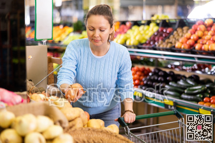 Positive middle-aged female buyer choosing onion in supermarket