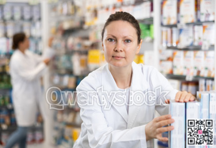 In pharmacy, woman chemist makes out showcase with warming analgesic ointments