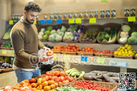 Man chooses tomatoes for purchase in greengrocer shop
