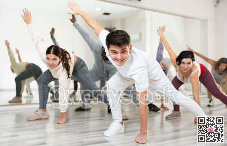 Smiling guy doing stretching warm-up before group dance class