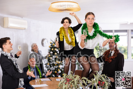 Excited girls dancing on table during New Year corporate party